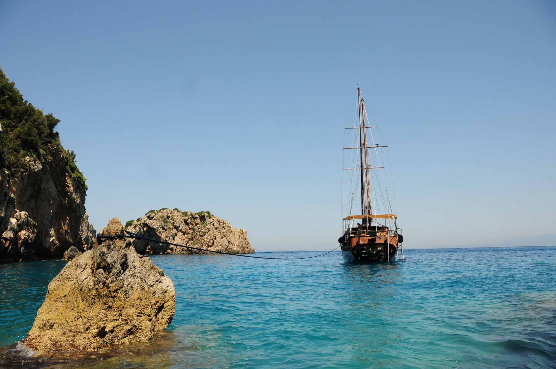 Sea Moon stern-tied to the rock in a turquoise cove in the Saronic Islands
