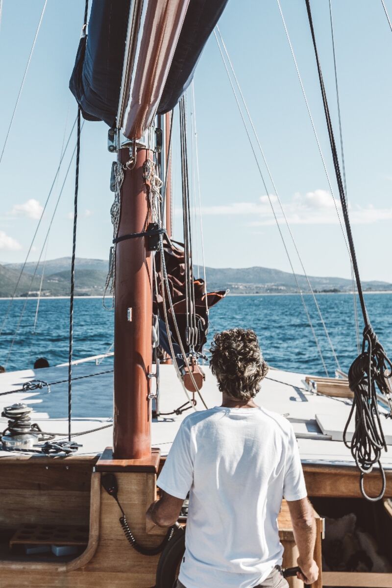 A guest at the helm with the mast and rigging in view
