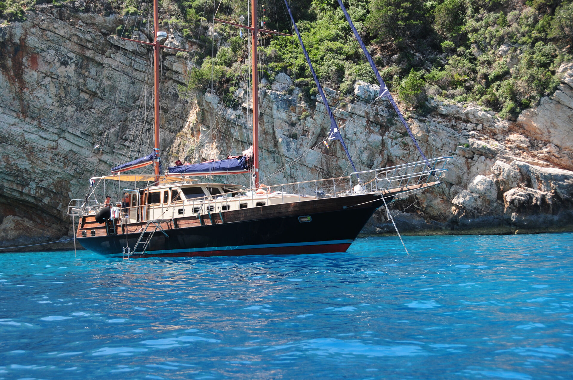 Sea Moon anchored beside a steep rocky cliff in the Greek Islands