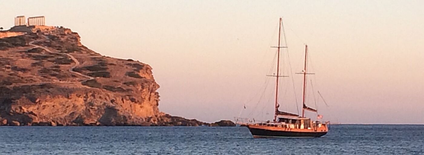 Sea Moon anchored near a rocky headland at sunset